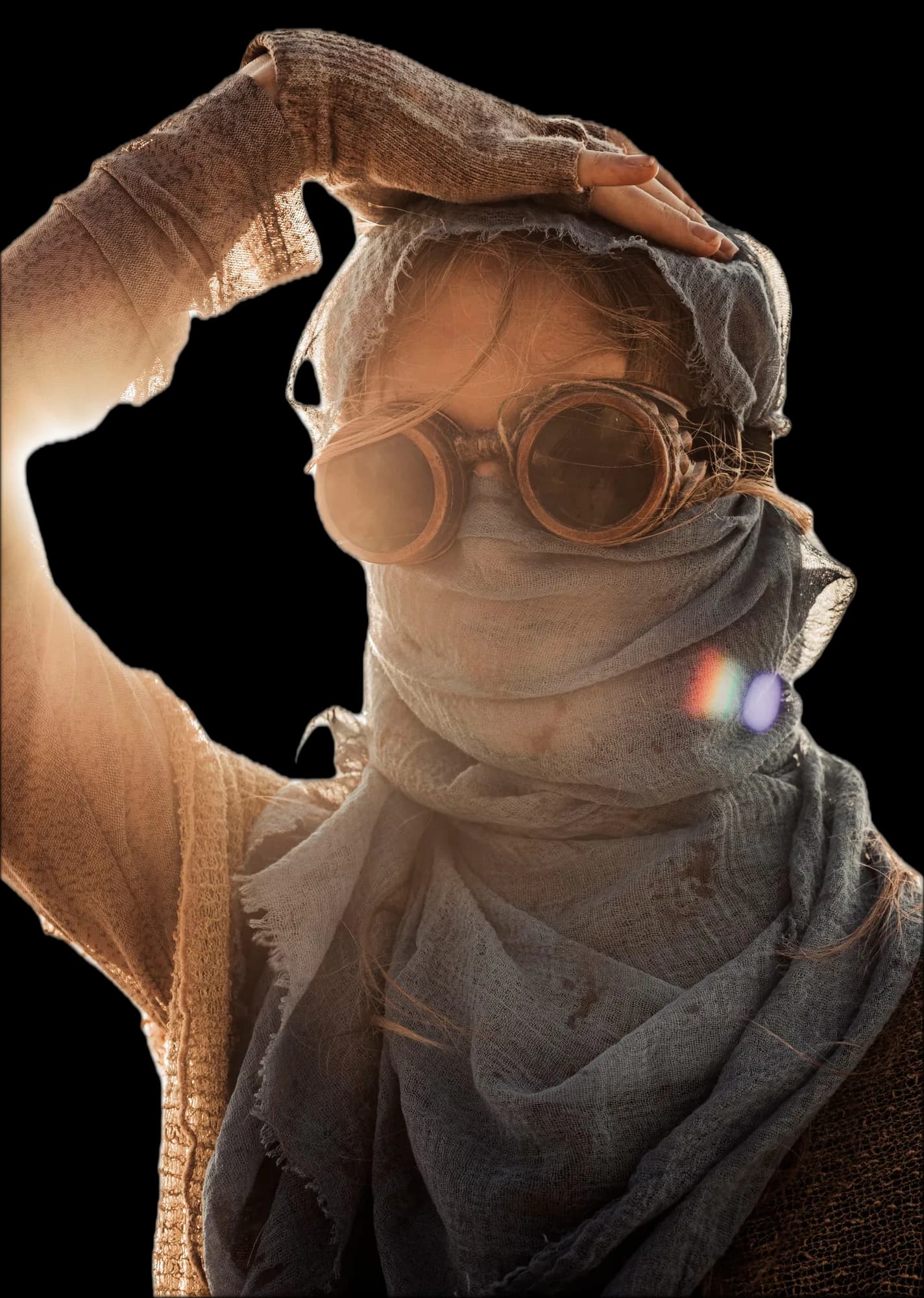 A young woman in strong backlight holds her hand over her head. Her face is covered by blue-grey gauze and copper goggles, and the sun glares behind her.
